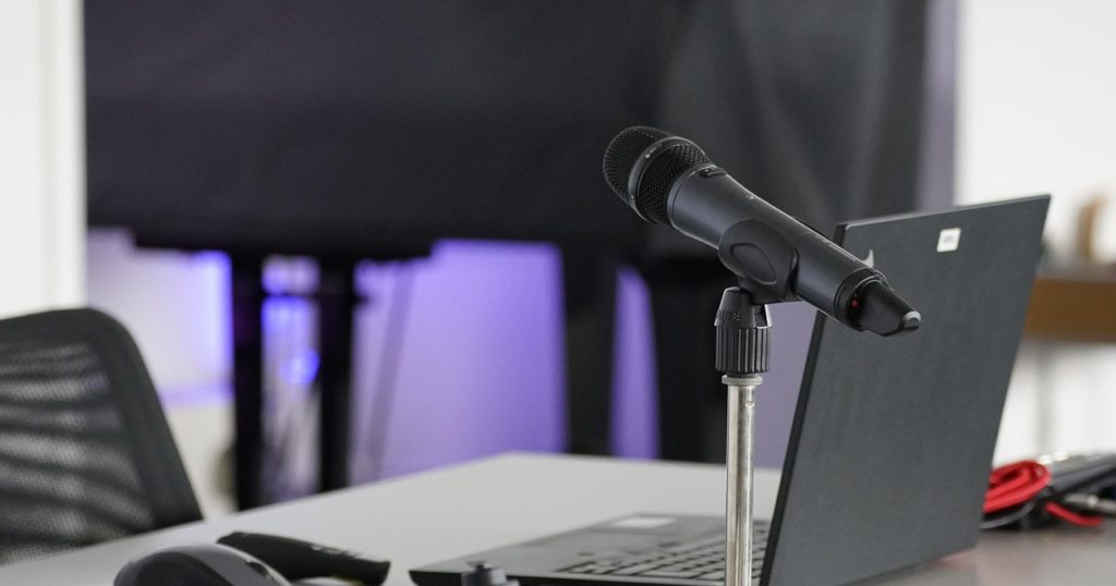 国際会議の通訳ブースをイメージしたマイクとノートパソコン